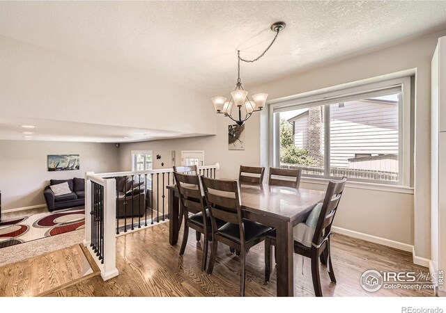 2447 E 100th Way, Thornton, CO 80229 - dining area with a chandelier, wood finished floors, baseboards, and a textured ceiling