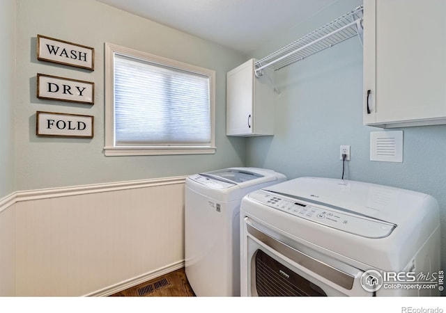 2447 E 100th Way, Thornton, CO 80229 - laundry room featuring cabinet space, washing machine and clothes dryer, a wainscoted wall, and wood finished floors