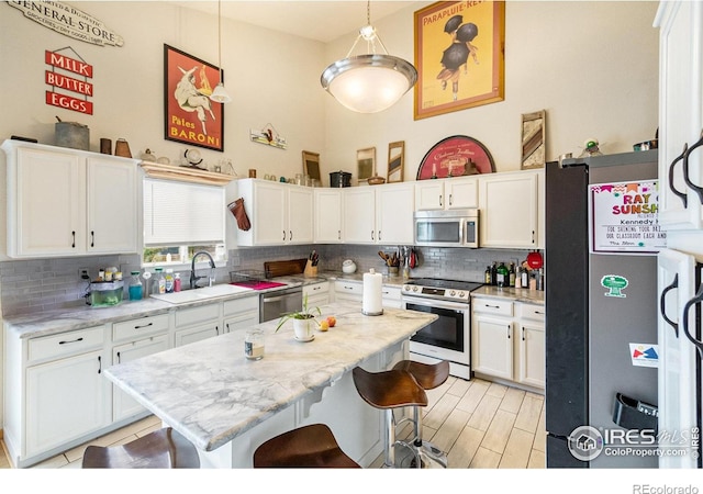 3328 Wild W Ln, Wellington, CO 80549 - kitchen featuring appliances with stainless steel finishes, tasteful backsplash, a kitchen bar, white cabinetry, and a high ceiling
