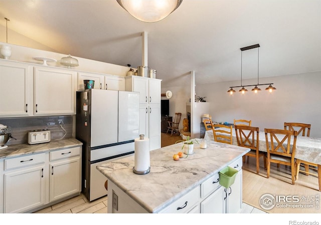 3328 Wild W Ln, Wellington, CO 80549 - kitchen with freestanding refrigerator, decorative backsplash, white cabinets, a kitchen island, and hanging light fixtures