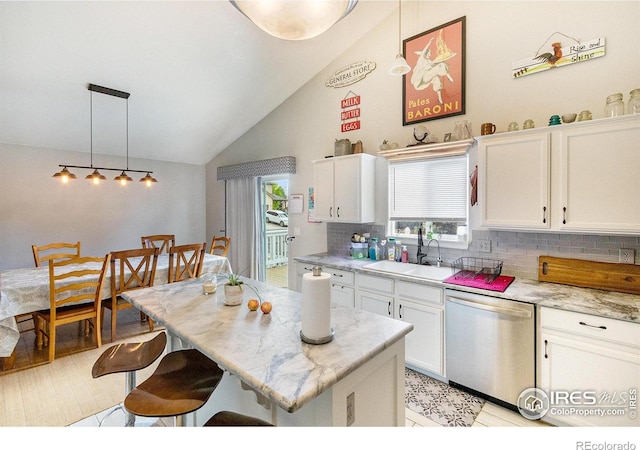 3328 Wild W Ln, Wellington, CO 80549 - kitchen featuring dishwasher, vaulted ceiling, tasteful backsplash, a breakfast bar area, and white cabinets