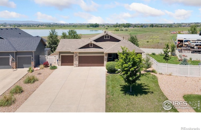 5869 Vinca Ave, Longmont, CO 80504 - view of front of home featuring a garage, concrete driveway, a water view, and stone siding
