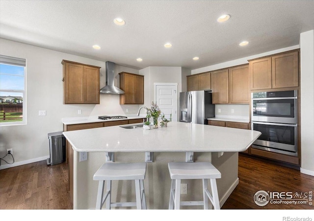 2150 Crop Row Dr, Windsor, CO 80550 - kitchen with appliances with stainless steel finishes, wall chimney exhaust hood, a sink, a center island with sink, and baseboards