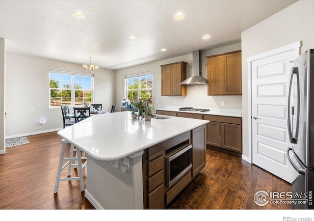 2150 Crop Row Dr, Windsor, CO 80550 - kitchen featuring wall chimney exhaust hood, appliances with stainless steel finishes, a chandelier, a center island, and a sink
