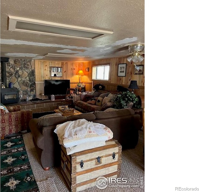 100 Santee Ct, Red Feather Lakes, CO 80545 - living room featuring a textured ceiling, a wood stove, wood walls, and a ceiling fan
