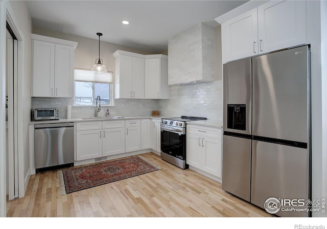 19810 County Road 1, Berthoud, CO 80513 - kitchen with appliances with stainless steel finishes, wall chimney exhaust hood, a sink, light countertops, and light wood-style floors