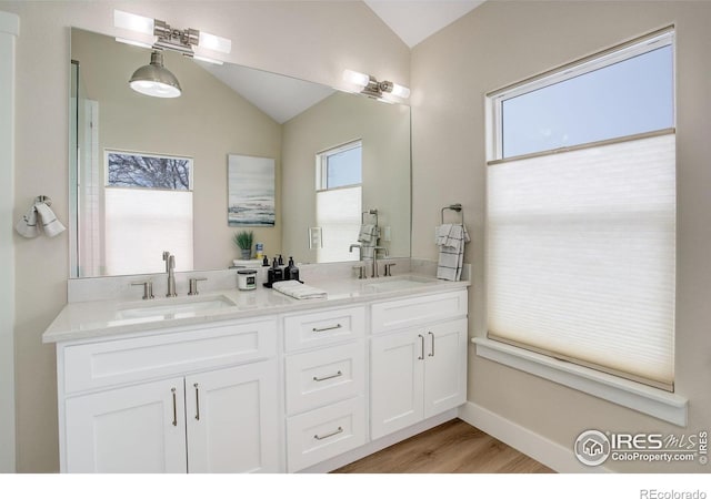 19810 County Road 1, Berthoud, CO 80513 - bathroom featuring vaulted ceiling, double vanity, plenty of natural light, and wood finished floors