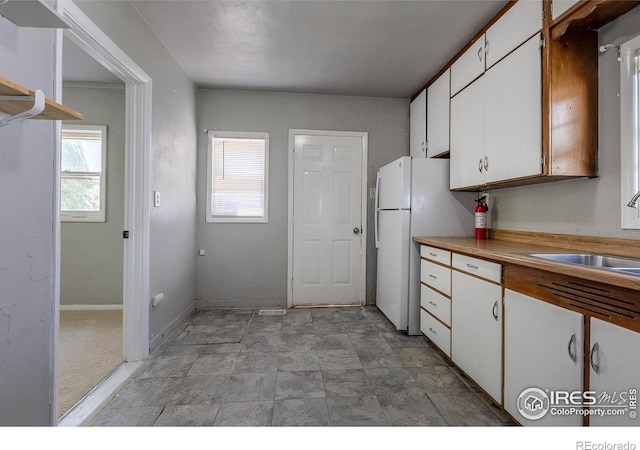 29 Marshall Pl, Longmont, CO 80504 - kitchen with white cabinets, freestanding refrigerator, a sink, and light countertops