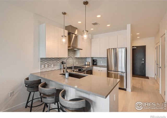 1616 S Broadway Unit 304, Denver, CO 80210 - kitchen featuring freestanding refrigerator, wall chimney exhaust hood, a peninsula, a sink, and tasteful backsplash