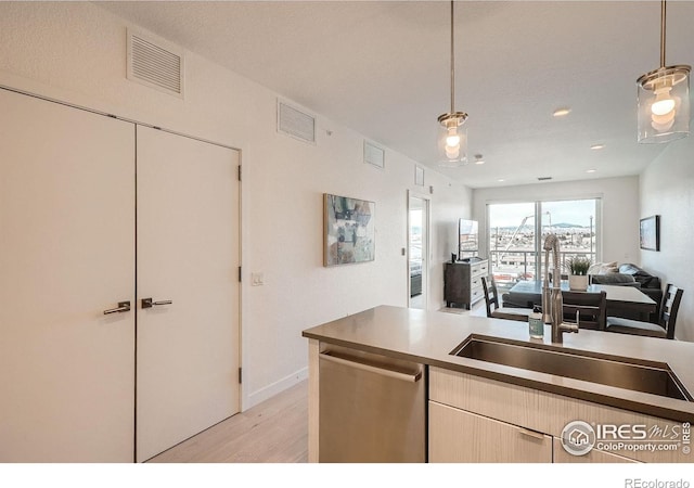 1616 S Broadway Unit 304, Denver, CO 80210 - kitchen with a sink, stainless steel dishwasher, light wood finished floors, open floor plan, and pendant lighting