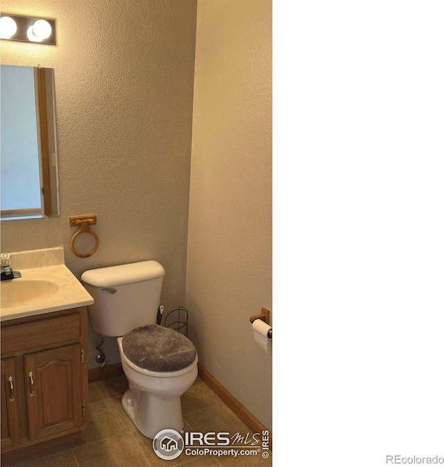 309 Ash Ct, Evans, CO 80620 - half bath with vanity, toilet, tile patterned flooring, and baseboards