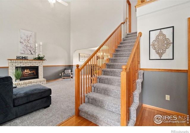 1202 Creekwood Ct, Windsor, CO 80550 - stairs with wood finished floors, baseboards, a fireplace, ceiling fan, and a high ceiling