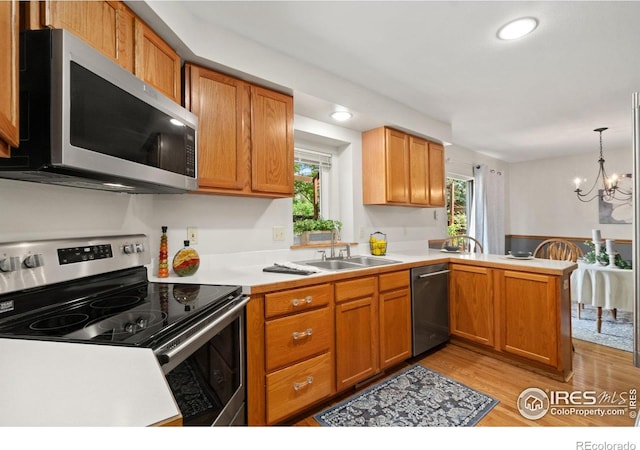 1202 Creekwood Ct, Windsor, CO 80550 - kitchen with appliances with stainless steel finishes, a sink, light wood-type flooring, a peninsula, and light countertops