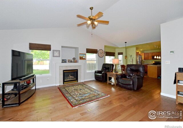 1131 Sandra Dr, Johnstown, CO 80534 - living area featuring wood finished floors, healthy amount of natural light, a ceiling fan, a fireplace, and high vaulted ceiling
