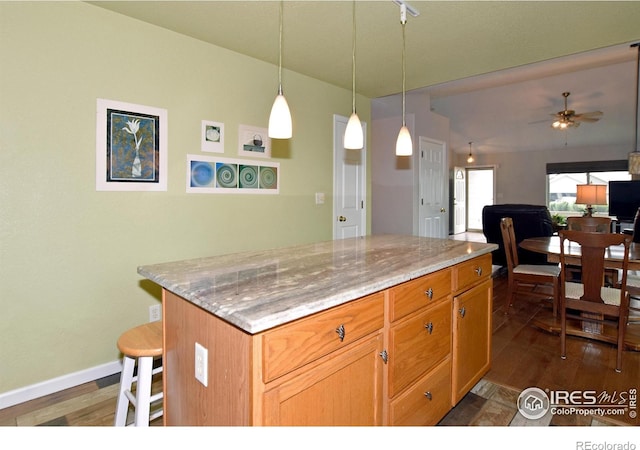 1131 Sandra Dr, Johnstown, CO 80534 - kitchen with dark wood-style floors, ceiling fan, a center island, and light stone countertops