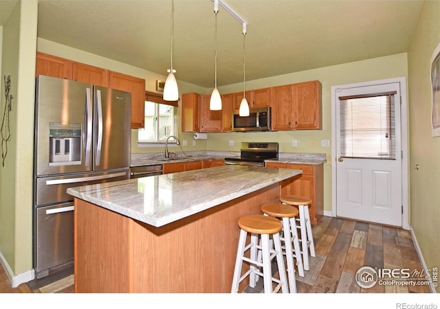 1131 Sandra Dr, Johnstown, CO 80534 - kitchen featuring stainless steel appliances, a kitchen bar, decorative light fixtures, dark wood-type flooring, and baseboards
