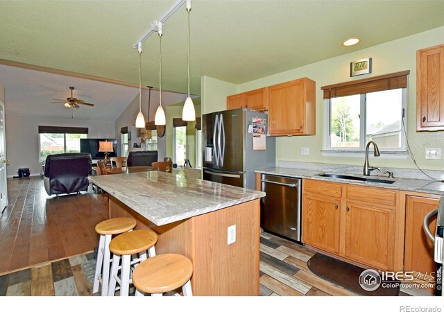 1131 Sandra Dr, Johnstown, CO 80534 - kitchen featuring a sink, appliances with stainless steel finishes, a kitchen island, a kitchen bar, and hanging light fixtures