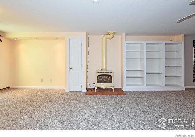 1131 Sandra Dr, Johnstown, CO 80534 - below grade area with a wood stove, carpet floors, and baseboards