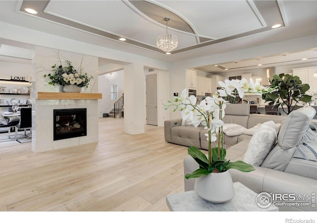 9527 Loveland Way, Arvada, CO 80007 - living area featuring recessed lighting, light wood-style flooring, a chandelier, a raised ceiling, and a fireplace