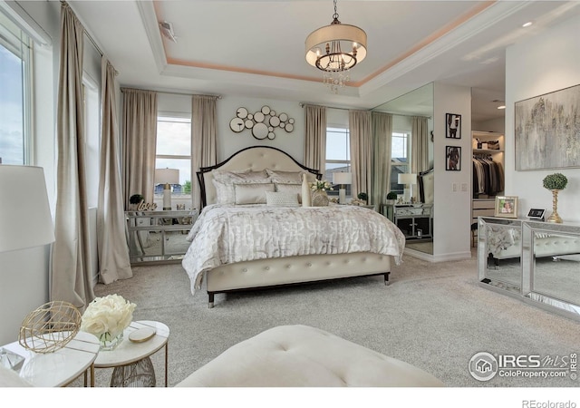 9527 Loveland Way, Arvada, CO 80007 - carpeted bedroom with a raised ceiling, a chandelier, ornamental molding, and a walk in closet