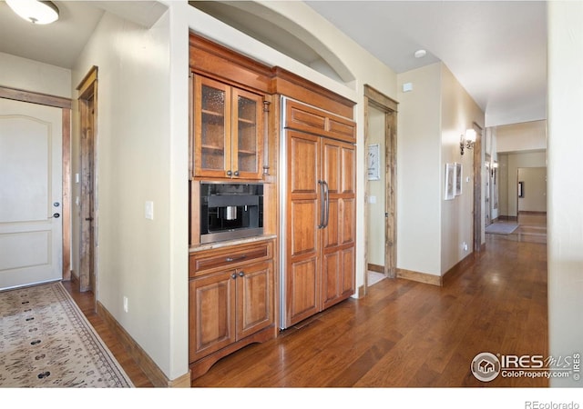 8236 County Road 74, Windsor, CO 80550 - kitchen featuring dark wood-type flooring, baseboards, glass insert cabinets, and brown cabinets
