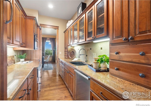 8236 County Road 74, Windsor, CO 80550 - kitchen featuring dishwasher, a sink, light stone countertops, brown cabinets, and tasteful backsplash