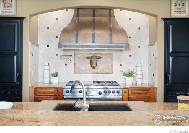 8236 County Road 74, Windsor, CO 80550 - kitchen featuring ventilation hood, light stone countertops, gas range, backsplash, and a sink