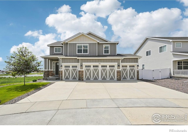 961 Mouflon Dr, Severance, CO 80550 - craftsman-style home featuring stone siding, board and batten siding, concrete driveway, an attached garage, and a gate