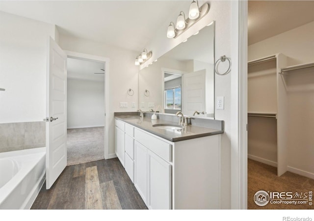 961 Mouflon Dr, Severance, CO 80550 - full bathroom with double vanity, a bath, wood finished floors, and a walk in closet
