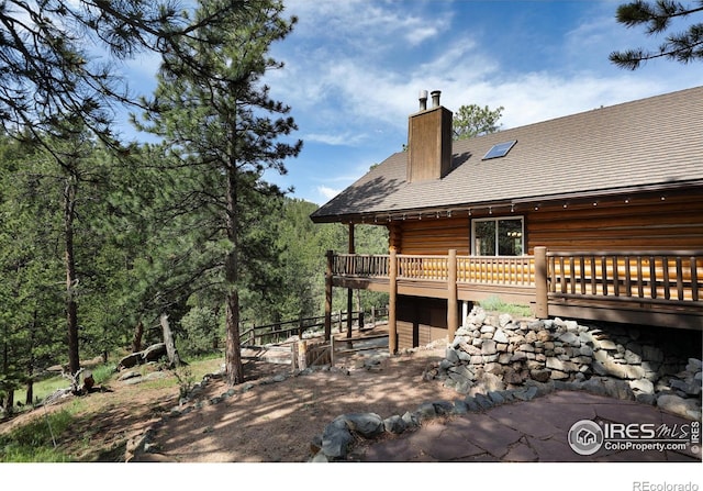 28 Ute Crossing Ct, Lyons, CO 80540 - rear view of house featuring a chimney, a deck, and log exterior