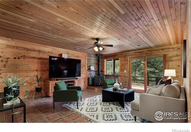 28 Ute Crossing Ct, Lyons, CO 80540 - living area with a wood stove, wooden walls, wood ceiling, a ceiling fan, and tile patterned flooring