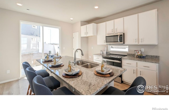 3356 Streamwood Dr, Johnstown, CO 80534 - kitchen with appliances with stainless steel finishes, a kitchen breakfast bar, light wood-style floors, light stone countertops, and recessed lighting
