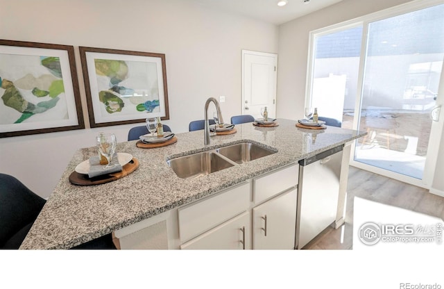 3356 Streamwood Dr, Johnstown, CO 80534 - kitchen with dishwasher, white cabinetry, light wood-style floors, light stone counters, and recessed lighting