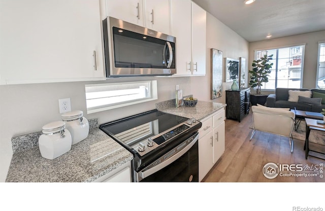 3356 Streamwood Dr, Johnstown, CO 80534 - kitchen with appliances with stainless steel finishes, white cabinetry, recessed lighting, light wood finished floors, and open floor plan
