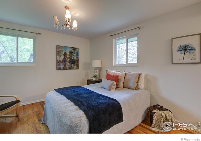 1110 Hartford Dr, Boulder, CO 80305 - bedroom featuring multiple windows, wood finished floors, a chandelier, and baseboards