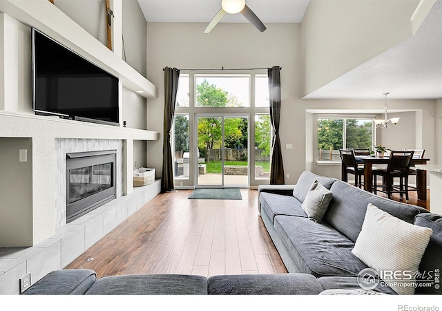 11740 Ivy St, Thornton, CO 80233 - living area with a towering ceiling, hardwood / wood-style floors, a chandelier, ceiling fan, and a tile fireplace