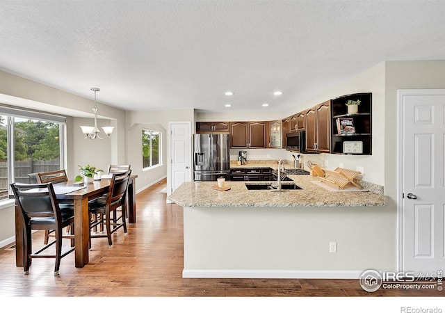 11740 Ivy St, Thornton, CO 80233 - kitchen featuring stainless steel appliances, a sink, dark brown cabinetry, light wood-style flooring, and a chandelier