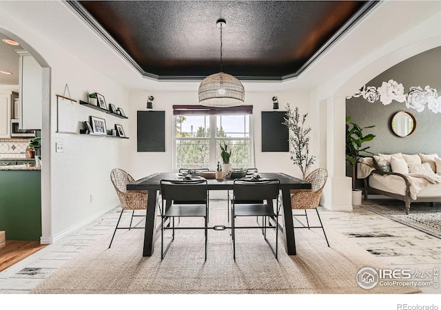 8839 Shetland Dr, Frederick, CO 80504 - dining space featuring a tray ceiling, arched walkways, and baseboards