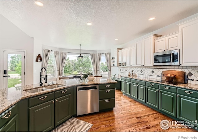 8839 Shetland Dr, Frederick, CO 80504 - kitchen with stainless steel appliances, a sink, white cabinetry, light wood finished floors, and green cabinetry