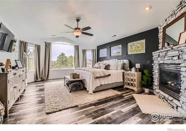8839 Shetland Dr, Frederick, CO 80504 - bedroom featuring dark wood-style flooring, lofted ceiling, a fireplace, and ceiling fan