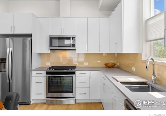 876 Cimarron Dr Unit B, Lafayette, CO 80026 - kitchen with stainless steel appliances, a sink, white cabinetry, backsplash, and light countertops