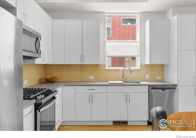876 Cimarron Dr Unit B, Lafayette, CO 80026 - kitchen with appliances with stainless steel finishes, a sink, light countertops, white cabinetry, and backsplash