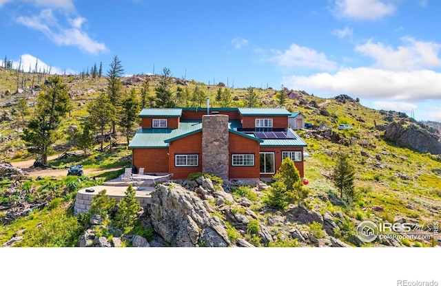 2507 Spencer Mountain Rd, Bellvue, CO 80512 - view of front facade featuring roof mounted solar panels, a mountain view, a chimney, and metal roof
