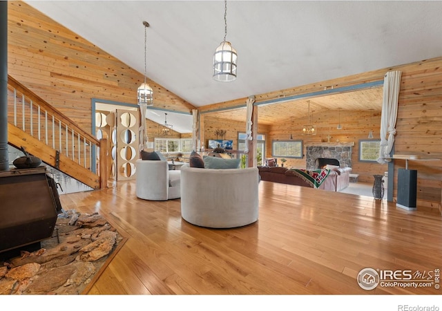 2507 Spencer Mountain Rd, Bellvue, CO 80512 - living room with wood walls, high vaulted ceiling, hardwood / wood-style floors, a stone fireplace, and a wood stove