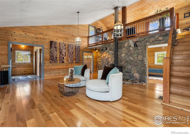 2507 Spencer Mountain Rd, Bellvue, CO 80512 - living room featuring high vaulted ceiling, wood walls, wood-type flooring, and a wood stove
