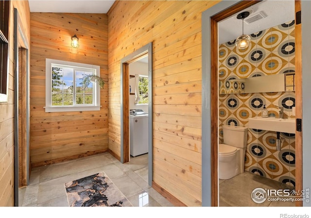 2507 Spencer Mountain Rd, Bellvue, CO 80512 - bathroom with toilet, wooden walls, a sink, and washer / dryer