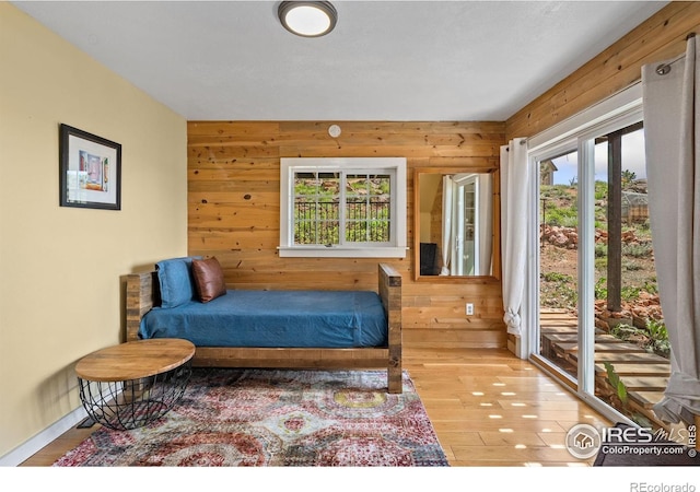 2507 Spencer Mountain Rd, Bellvue, CO 80512 - bedroom featuring multiple windows, wooden walls, access to outside, and wood finished floors