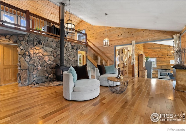 2507 Spencer Mountain Rd, Bellvue, CO 80512 - living area featuring a wood stove, wood walls, high vaulted ceiling, and wood-type flooring