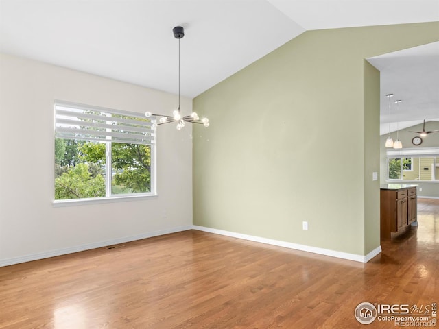 603 Summer Hawk Dr, Longmont, CO 80504 - empty room with vaulted ceiling, plenty of natural light, a chandelier, wood finished floors, and baseboards