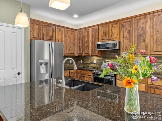 603 Summer Hawk Dr, Longmont, CO 80504 - kitchen featuring appliances with stainless steel finishes, a sink, backsplash, hanging light fixtures, and brown cabinetry